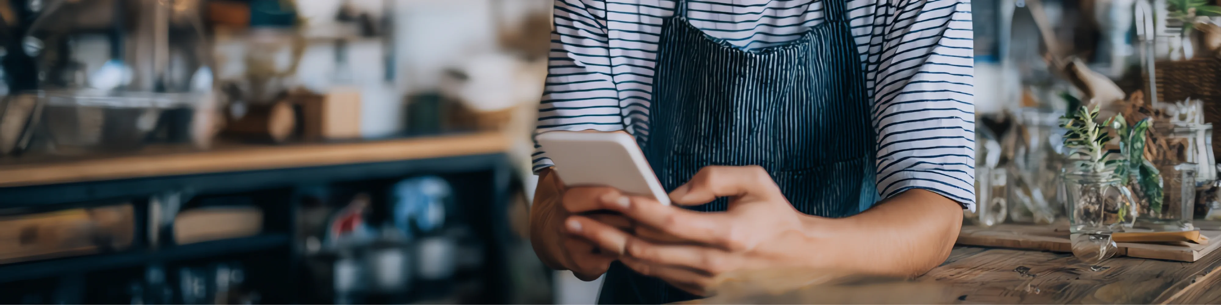 Ondernemer bekijkt telefoon in zijn keuken